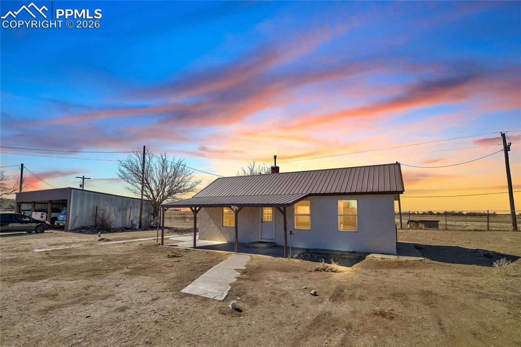 Image 4 of 49: Back of property at dusk with brick siding and a patio