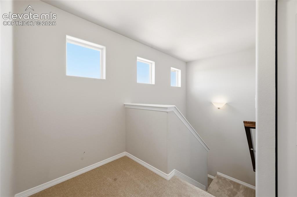 Image 13 of 30: Upper-level landing featuring three rectangular windows, neutral wall tones