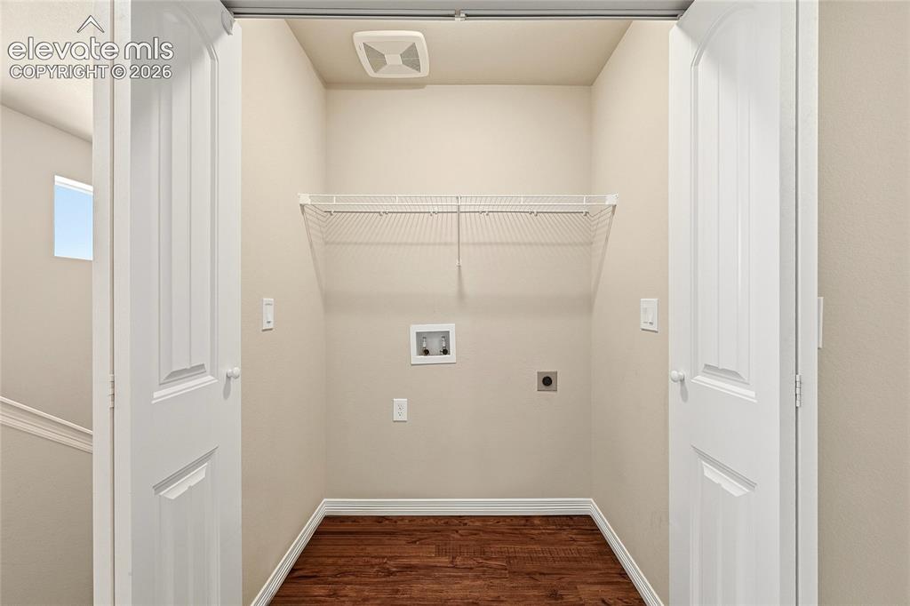 Image 14 of 30: Dedicated laundry alcove featuring wood-finish flooring, a white wire shelf