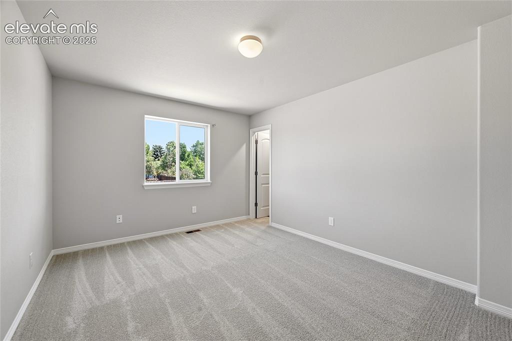 Image 19 of 30: Neutral-toned room featuring light gray carpet, white baseboards, and a win