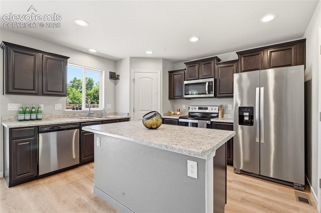 Image 2 of 30: Modern kitchen featuring dark wood cabinetry, stainless steel appliances, a