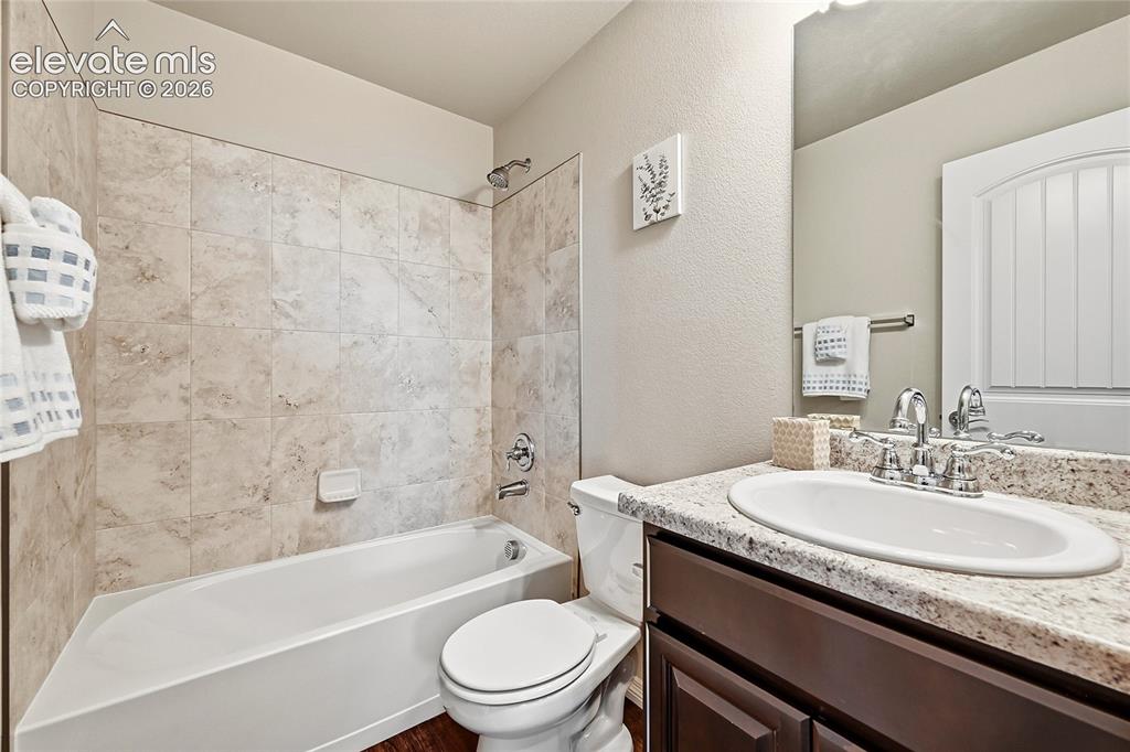 Image 21 of 30: Bathroom featuring a built-in tub with neutral-toned tile surround, single