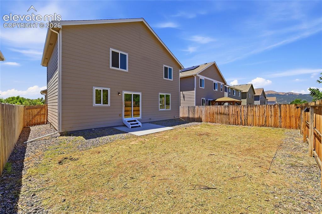 Image 24 of 30: Spacious backyard featuring a full wood privacy fence and a rear patio