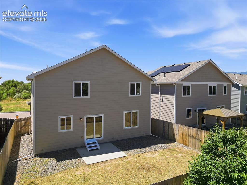 Image 25 of 30: Rear exterior featuring tan siding, a concrete patio, and a sliding glass d