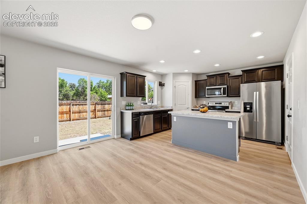 Image 3 of 30: Open-concept kitchen and dining area featuring light wood-finish flooring,