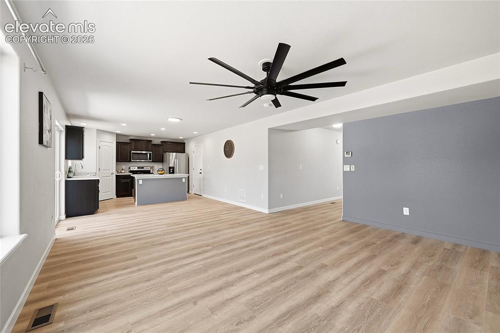 Image 4 of 30: Spacious open-concept living area featuring wood-finish flooring, a modern