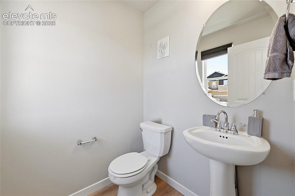 Image 7 of 30: Pedestal sink with chrome fixtures and a circular mirror