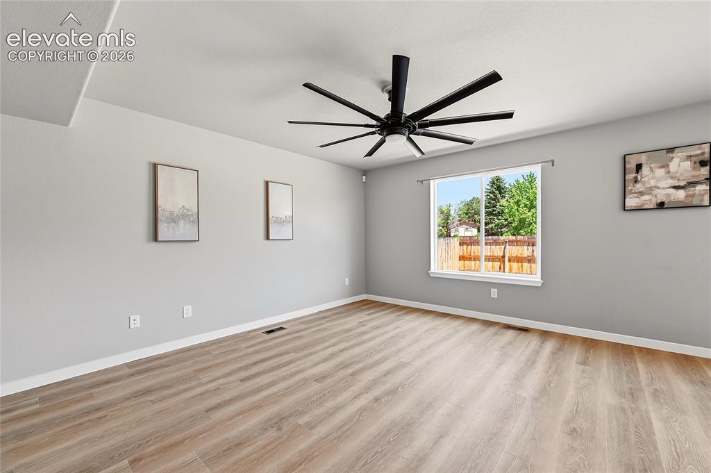 Image 9 of 30: Spacious room featuring wood-finish flooring, a large window, a modern blac