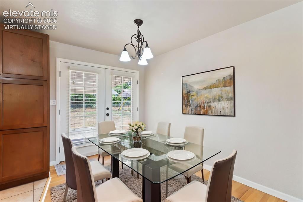Image 7 of 21: Virtually Staged dining room with French doors leading out to the covered p