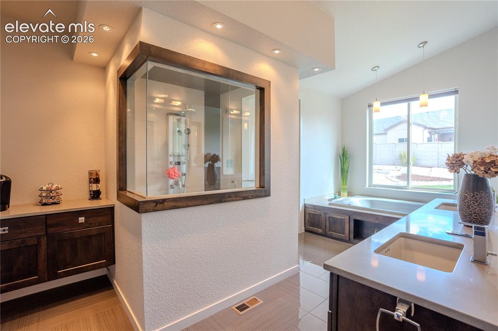 Image 25 of 50: View of walk in steam shower, coffee bar, double vanity and jetted tub