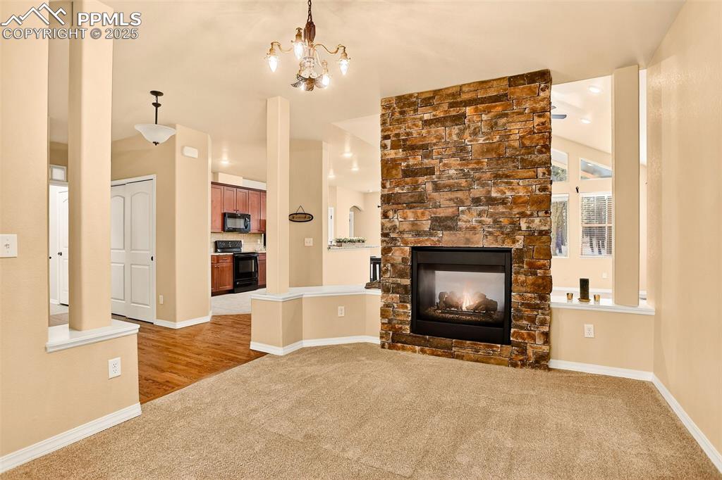 Image 13 of 45: Formal Dining room with new light carpet, a stone fireplace, and a chandeli