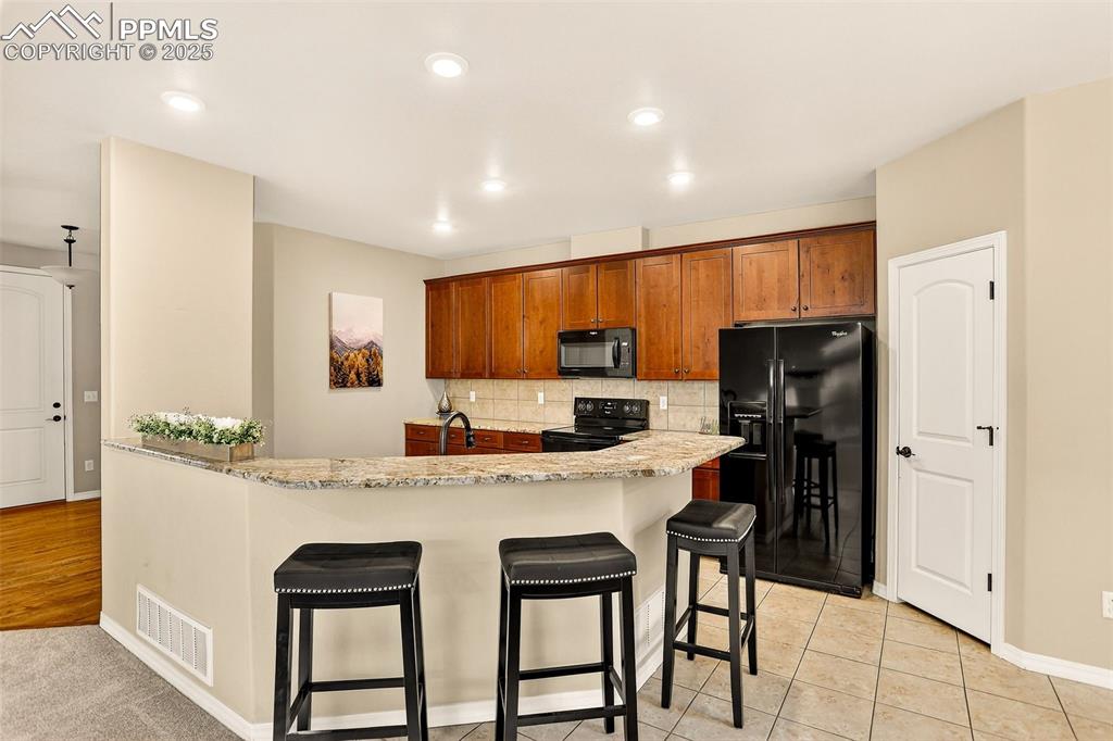 Image 17 of 45: Kitchen with decorative backsplash, solid wood cabinetry, walk in pantry, a