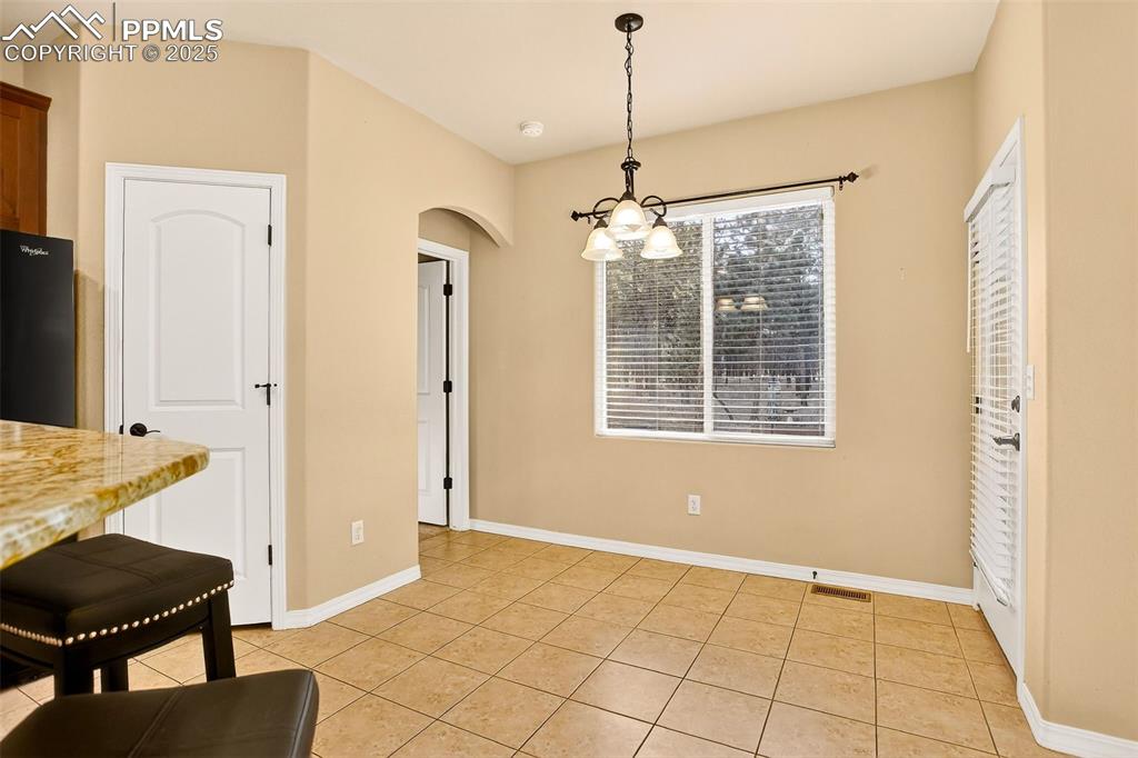 Image 19 of 45: Dining area off of kitchen featuring light tile patterned floors, arched wa