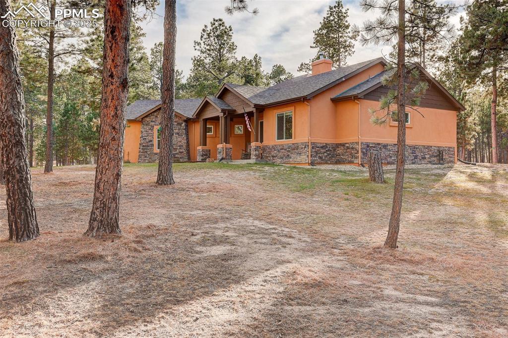 Image 2 of 45: View of front of home with stone siding, a chimney, covered porch, and stuc