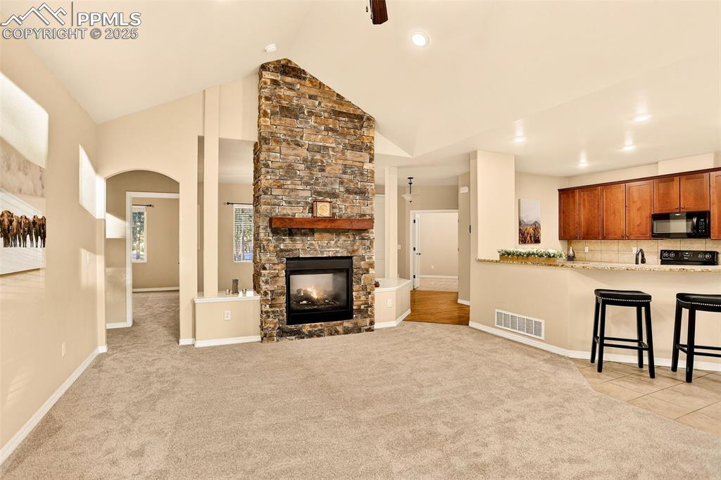 Image 21 of 45: Living room with new light colored carpet, a stone fireplace, arched walkwa