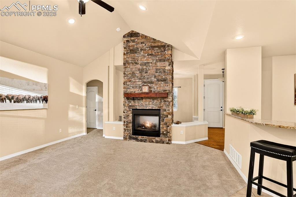 Image 23 of 45: Great Room featuring a fireplace, new carpet , a ceiling fan, arched walkwa