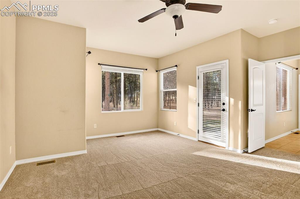 Image 24 of 45: Primary  bedroom with access to back patio with light colored carpet, healt