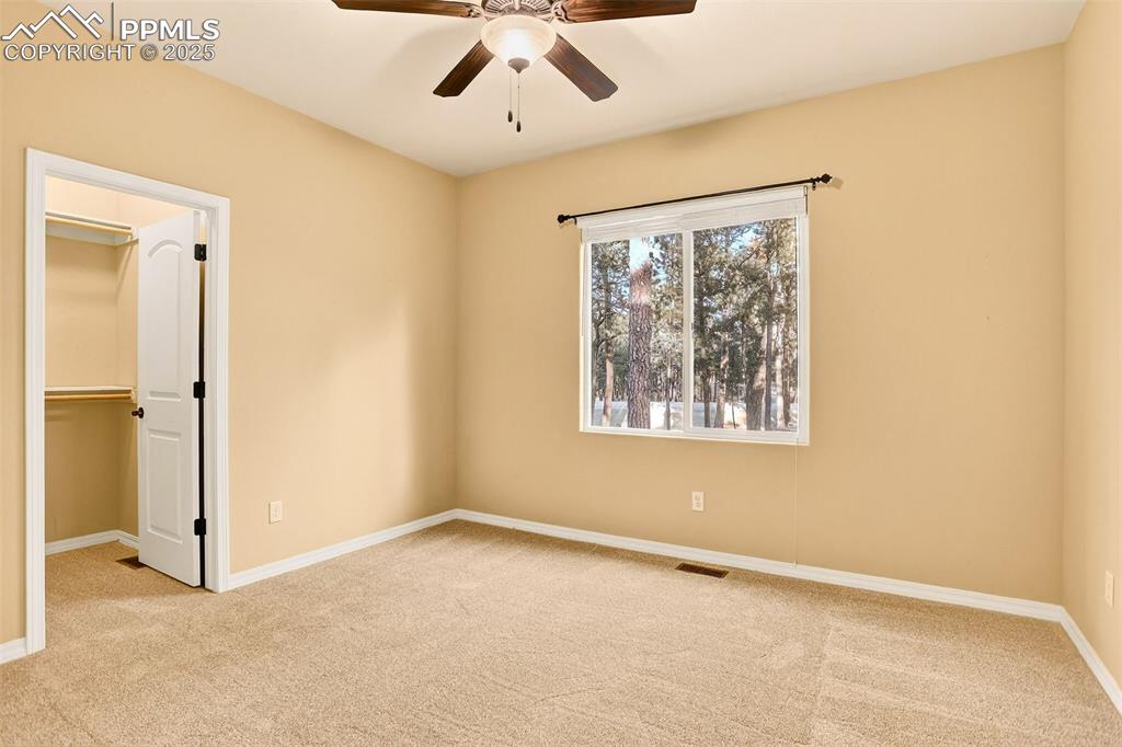 Image 27 of 45: Second bedroom featuring light carpet, a walk in closet, and ceiling fan
