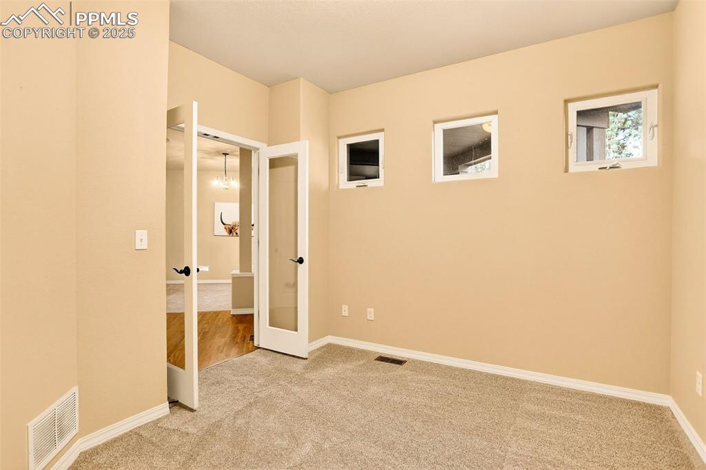 Image 40 of 45: Unfurnished bedroom featuring carpet flooring, french doors, and a chandeli
