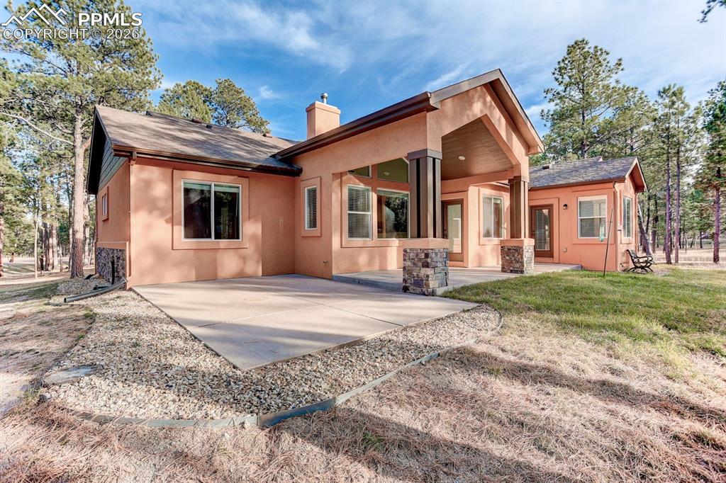 Image 41 of 45: Back of property featuring a chimney, a patio area, stucco siding, a yard, 