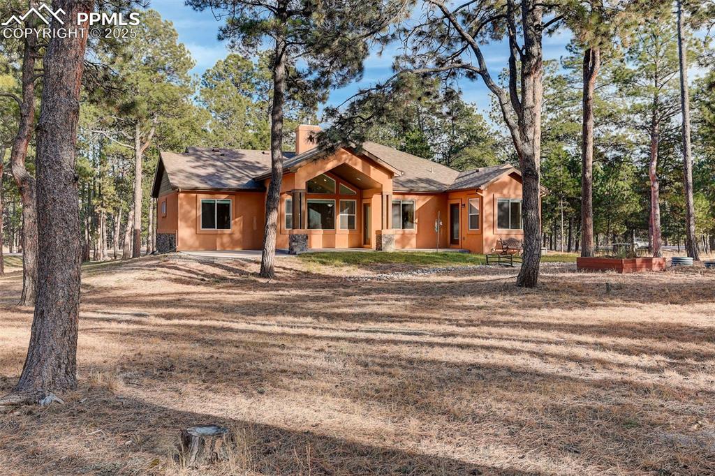 Image 42 of 45: View of back facade featuring a shingled roof and view of scattered trees, 