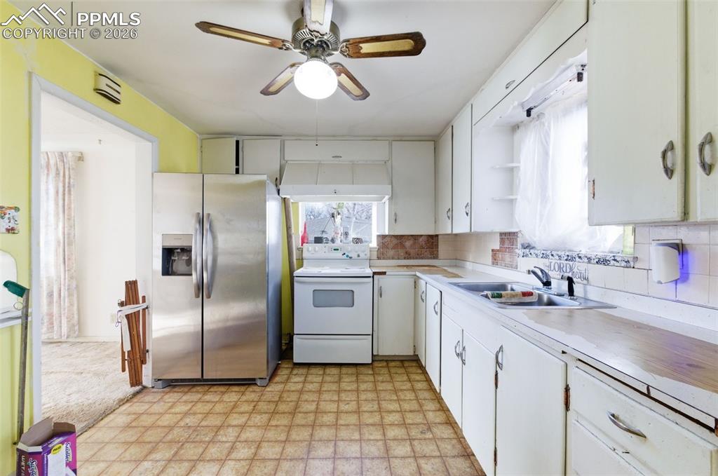 Image 10 of 35: Kitchen with light floors, stainless steel fridge with ice dispenser, light