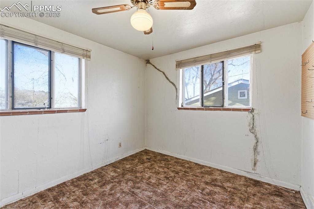 Image 16 of 35: Spare room featuring dark colored carpet and a ceiling fan