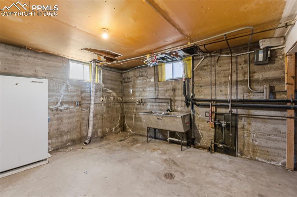 Image 21 of 35: Basement featuring freestanding refrigerator and plenty of natural light