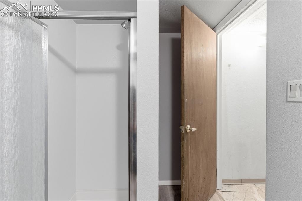 Image 30 of 35: Bathroom with a stall shower and a textured wall