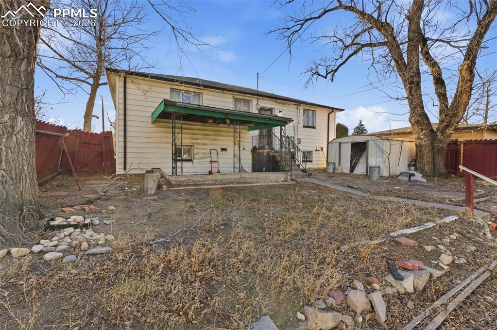 Image 32 of 35: Rear view of house with a fenced backyard, a storage unit, and a gate