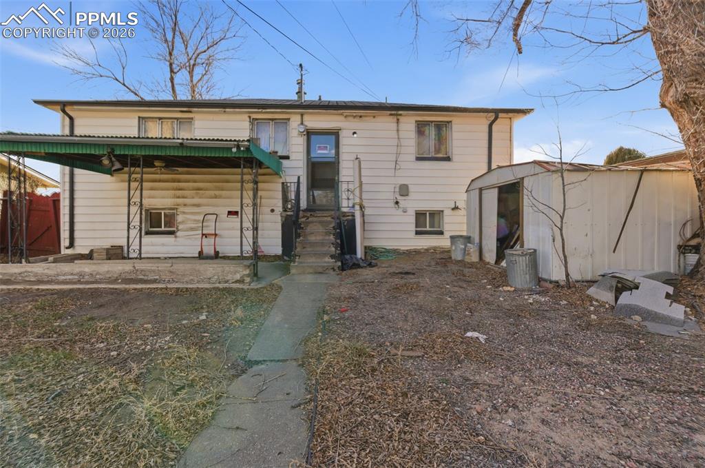 Image 33 of 35: Back of house featuring a storage unit and a porch