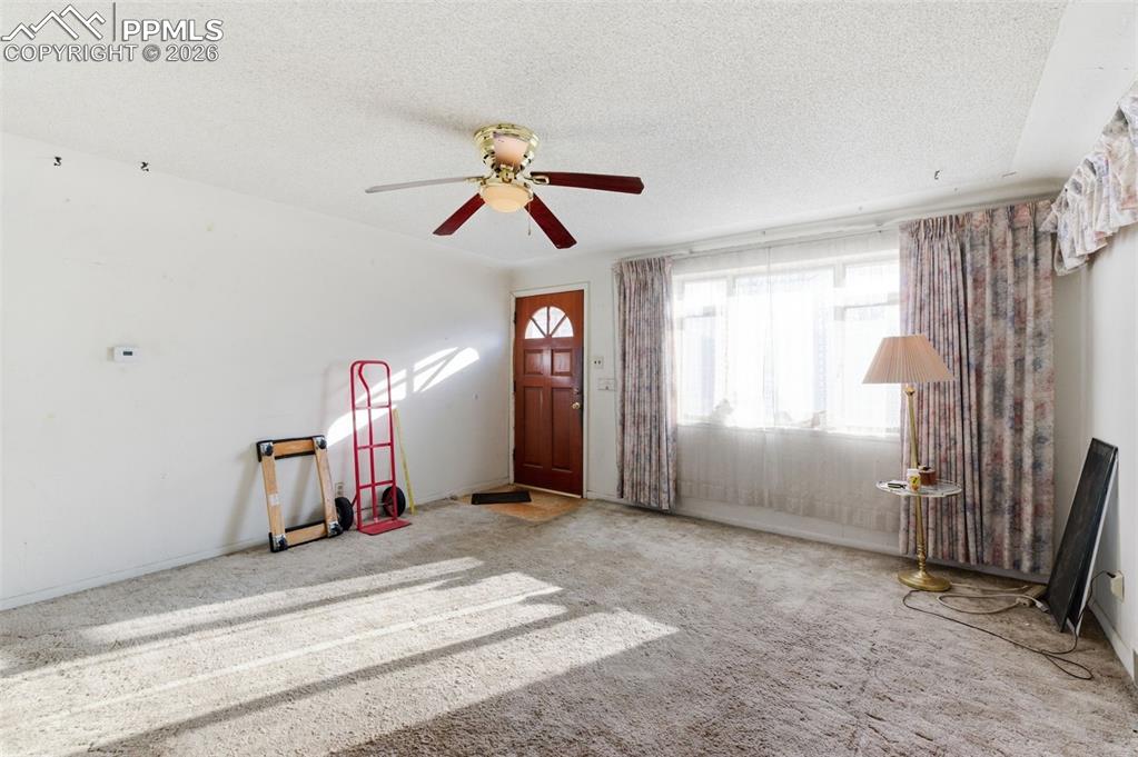 Image 7 of 35: Carpeted entrance foyer with a textured ceiling and ceiling fan