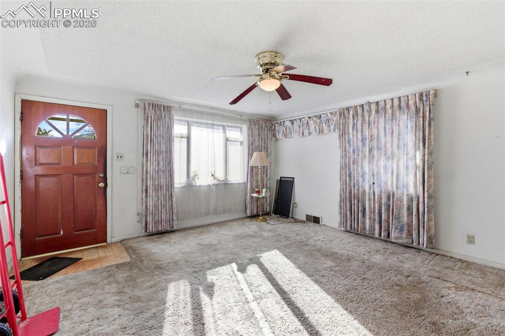 Image 8 of 35: Entrance foyer with carpet floors, ceiling fan, and a textured ceiling