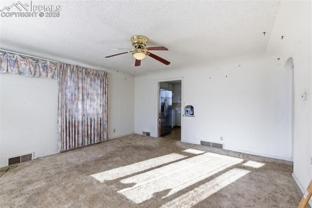 Image 9 of 35: Spare room with a textured ceiling, a ceiling fan, carpet, and arched walkw