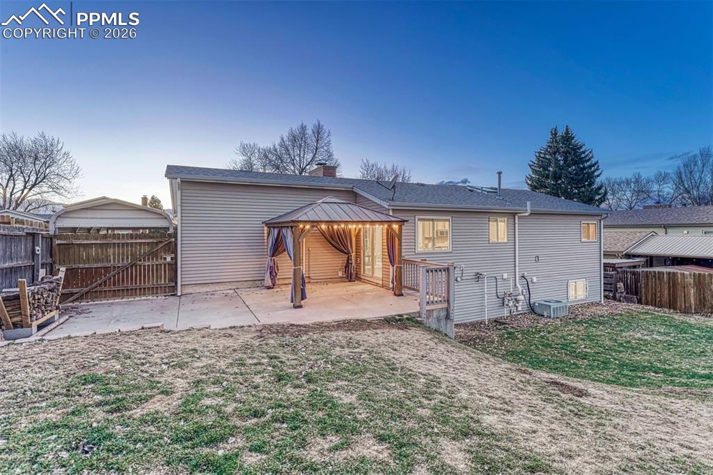 Image 38 of 49: Large patio and big gate at back of carport