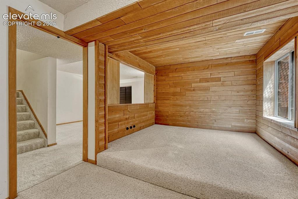 Image 11 of 48: Basement Bedroom #3 (non conforming) with neutral carpet and wood paneled w