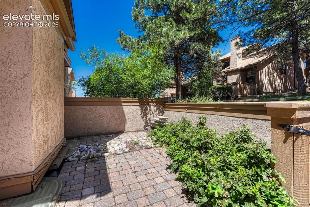 Image 18 of 48: Front courtyard that overlooks peaceful green space with mature trees linin