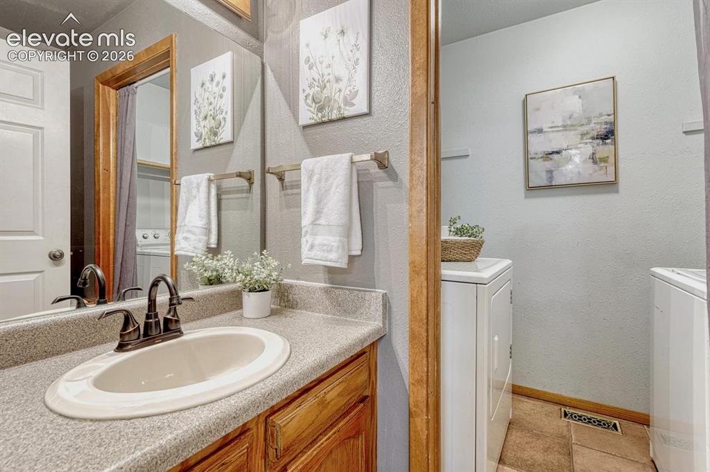 Image 25 of 48: The powder bathroom has a vanity and mirror and entrance into the laundry r