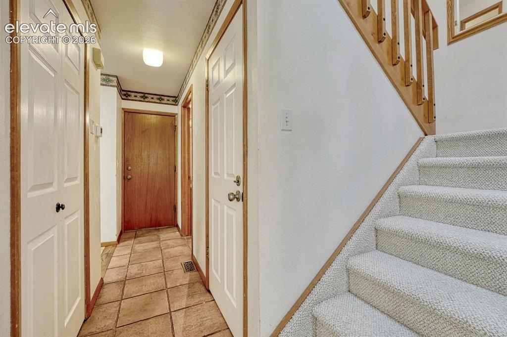 Image 27 of 48: Hallway with garage access and stairs to the upper level.