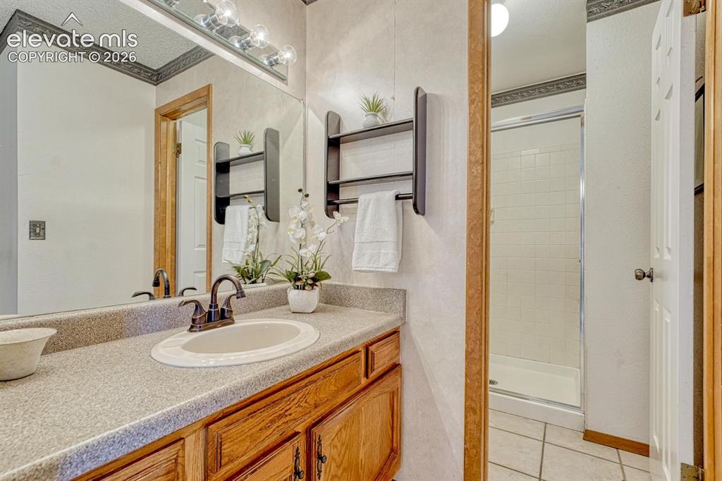 Image 34 of 48: The primary bathroom offers a vanity, mirror, and tiled shower with built-i