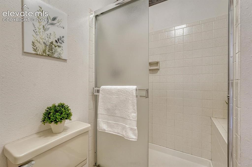 Image 35 of 48: Primary bathroom with tiled shower and built-in seat.