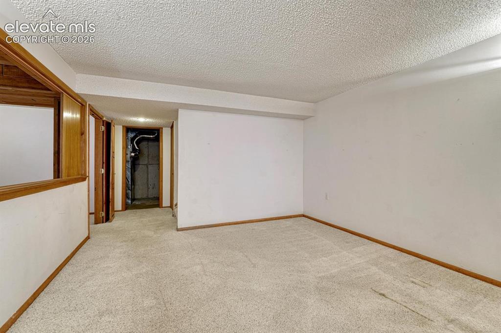 Image 39 of 50: Basement family room with view into the utility area.