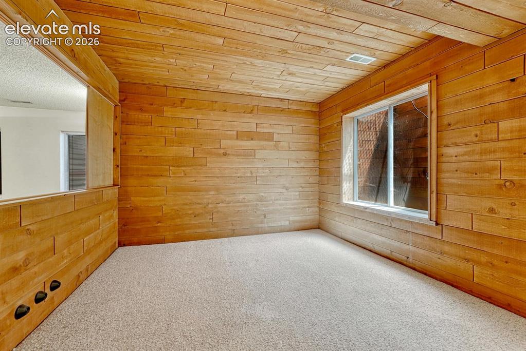 Image 39 of 48: Basement bedroom #3 has wood paneled walls and ceiling.
