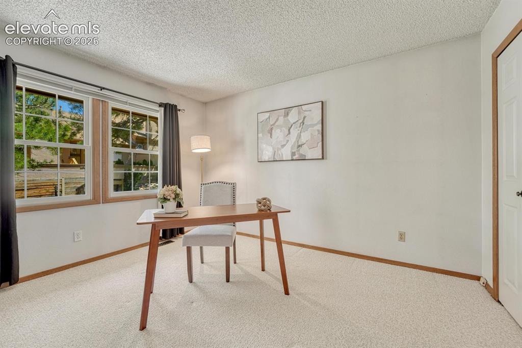 Image 8 of 48: Upper Level Bedroom #2 (currently an office) has neutral carpet, large wind
