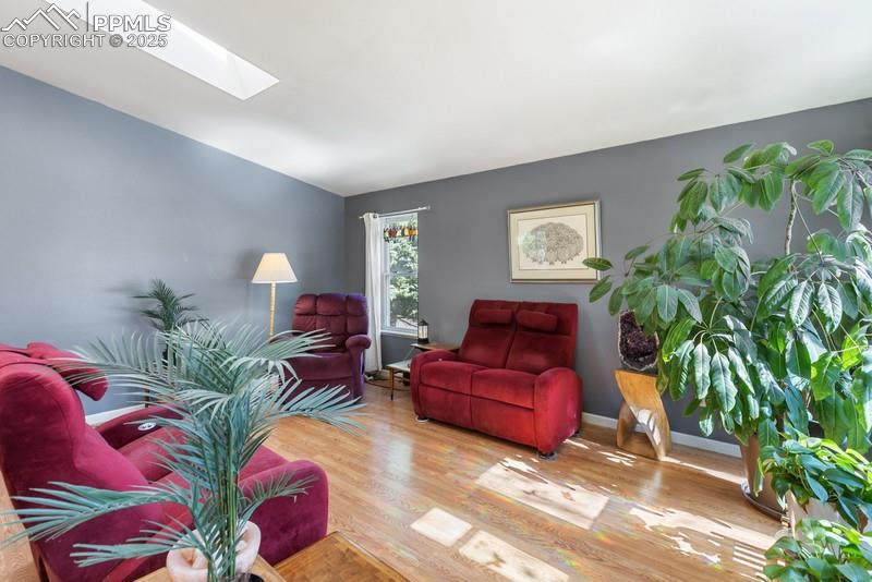 Image 11 of 29: Living room featuring wood finished floors, a skylight, and lofted ceiling