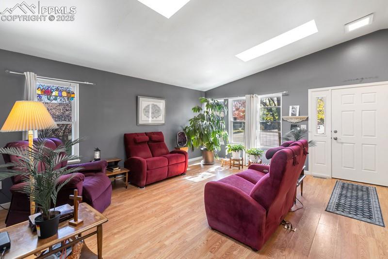 Image 12 of 29: Living room with lofted ceiling, wood finished floors, and a skylight