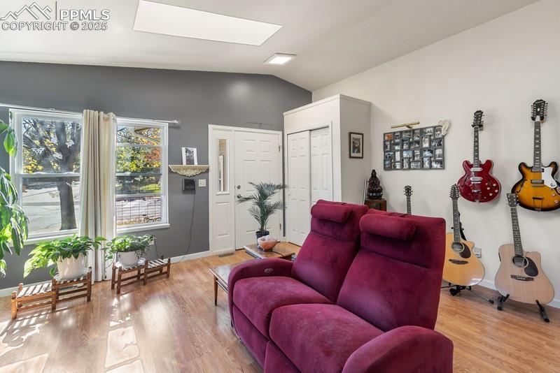 Image 13 of 29: Living area with vaulted ceiling, a skylight, and light wood finished floor