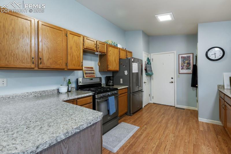 Image 14 of 29: Kitchen featuring range with gas stovetop, light wood-style floors, brown c