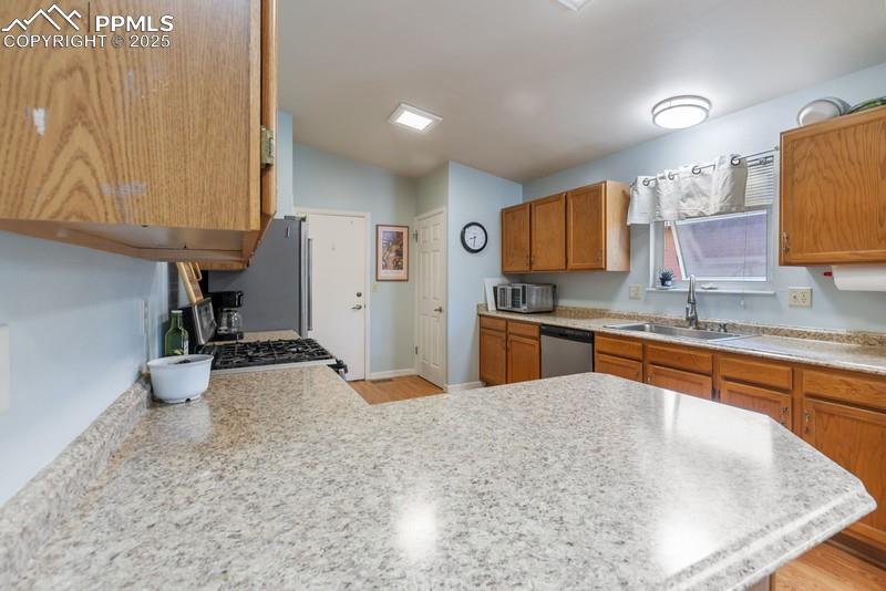 Image 16 of 29: Kitchen featuring brown cabinetry, light countertops, light wood-style floo