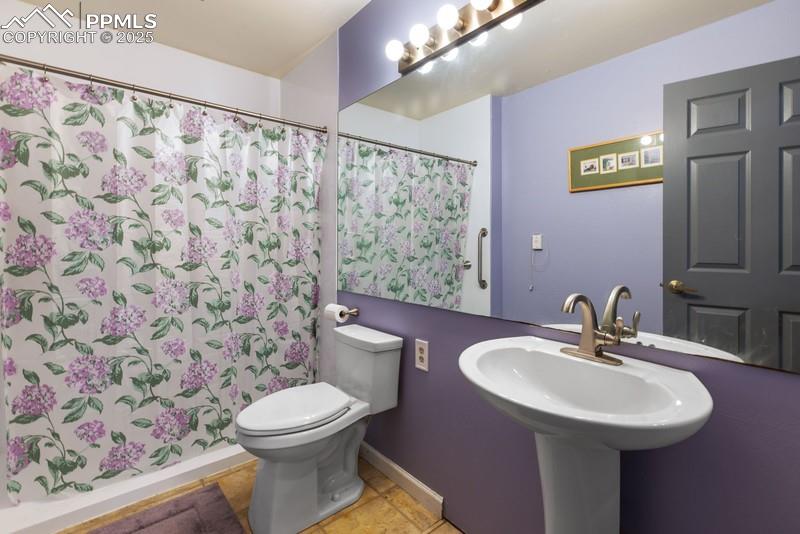 Image 27 of 29: Bathroom with curtained shower and light tile patterned floors